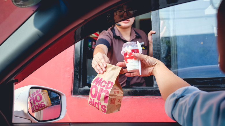 A customer grabbing food from a McDonald's drive-thru window