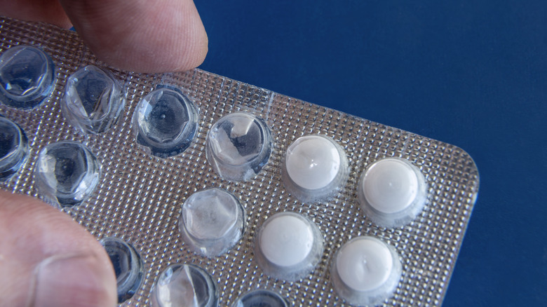 Close-up of a hand holding a blister pack with white tablets
