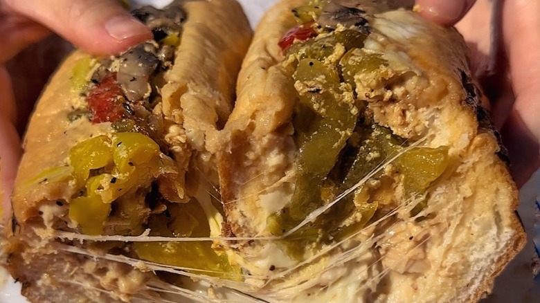 Someone holding a Philly cheesesteak from College Boy CheesesteaKs