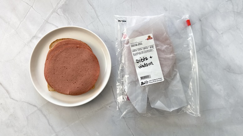 sliced bologna on bread with package of Dietz & Watson bologna alongside