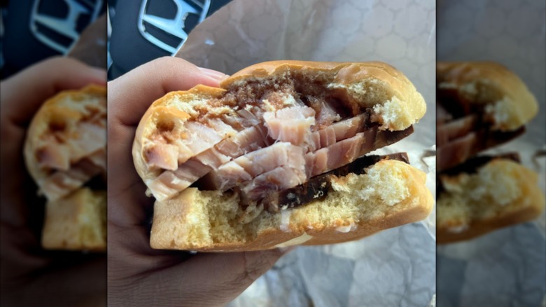 A close-up of a hand holding a half-eaten barbecue turkey sandwich from Buc-ee's