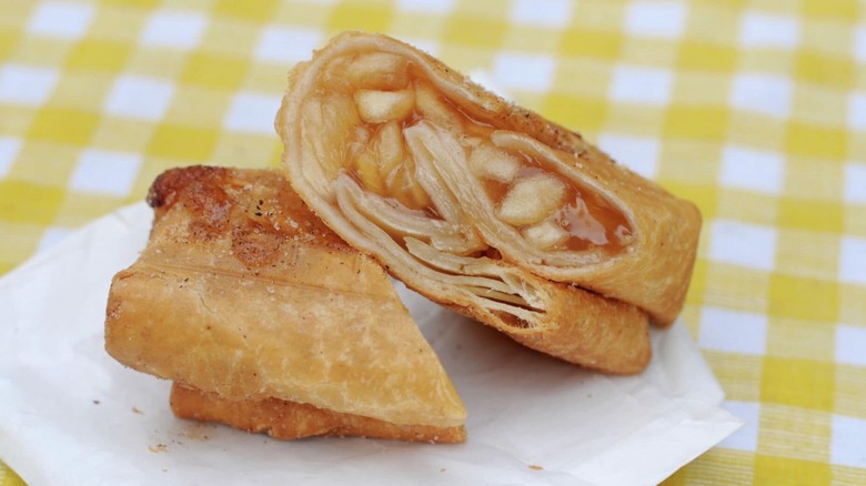 A Buc-ee's fried apple pie cut in half on a yellow checkered tablecloth
