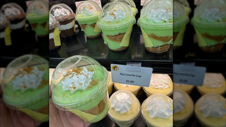 A hand holds a key lime pie cup in front of a shelf of more pudding cups at Buc-ee's