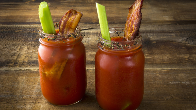 Two mason jars with bloody Caesars on wooden table