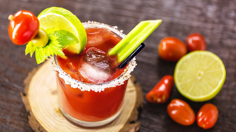 Rimmed Caesar drink garnished with celery lime and tomatoes