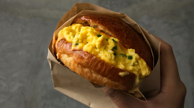 Hand holding the Fairfax breakfast sandwich at Eggslut