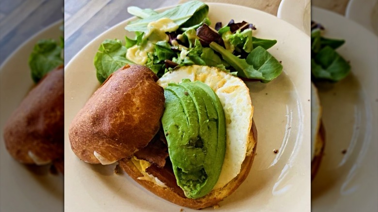 Egg, avocado, and bacon breakfast sandwich with salad at Le Pain Quotidien