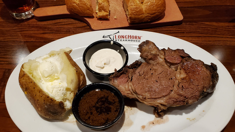 Prime rib and baked potato with two sauces at LongHorn Steakhouse