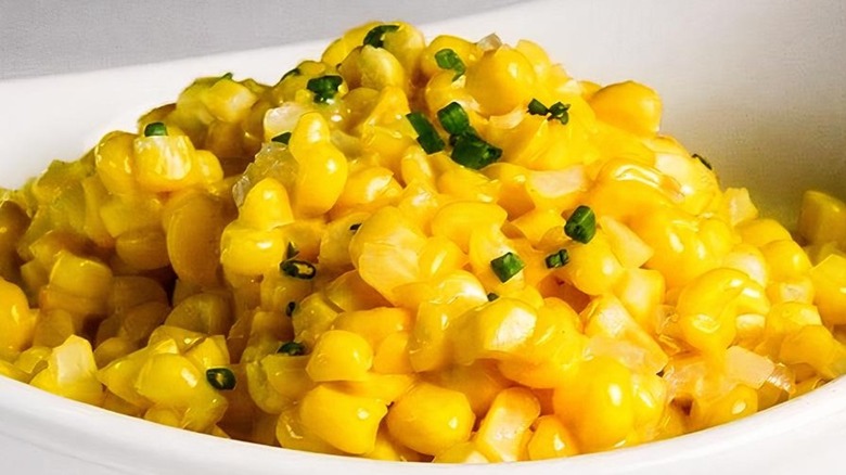 Closeup of buttery corn with chives on top in a bowl