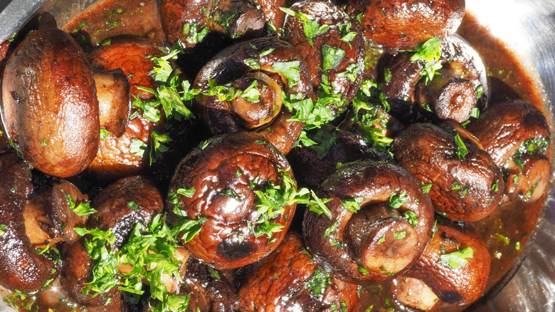 A bowl full of marinated mushrooms with a garnish sprinkled on top