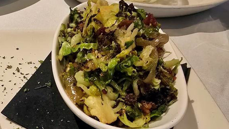 Bowl of shaved brussels sprouts on top of a black napkin and white plate