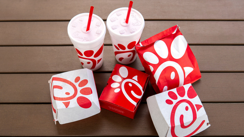Various Chick-fil-A wrappers and cups on a brown table