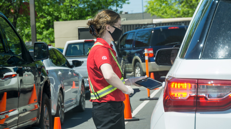 Chick-fil-A worker taking order at person's window in drive-thru line
