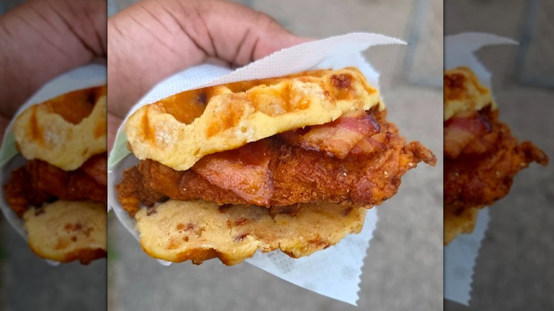 Hand holding Chick-fil-A chicken and waffle sandwich