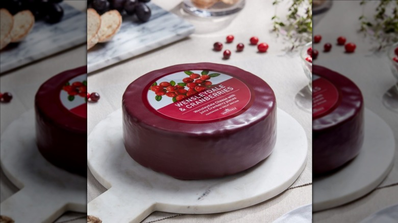 Red wax-covered wheel of Somerdale Cranberry Wensleydale on white board