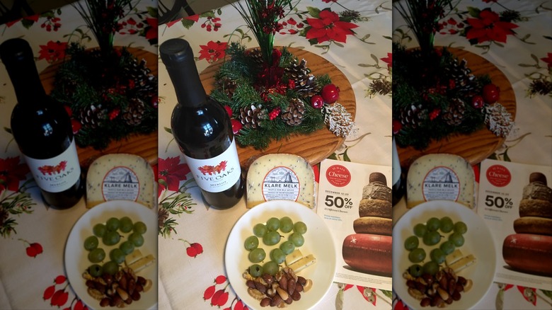 Klare Melk Raw Gouda Truffle on plate with grapes and nuts next to bottle of wine