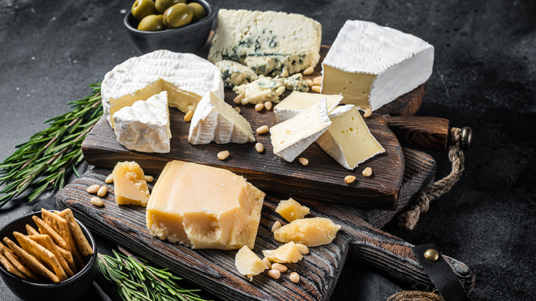 Various cheese on wooden boards with olives and crackers
