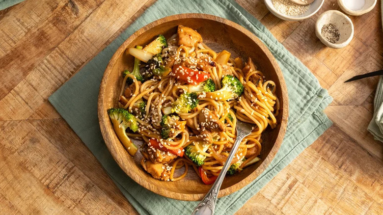 Spicy Chicken and Broccoli Noodles in wooden bowl on towel