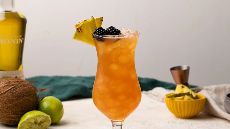 Fruity Rum Runner in a hurricane glass with pineapple and blackberry garnish.