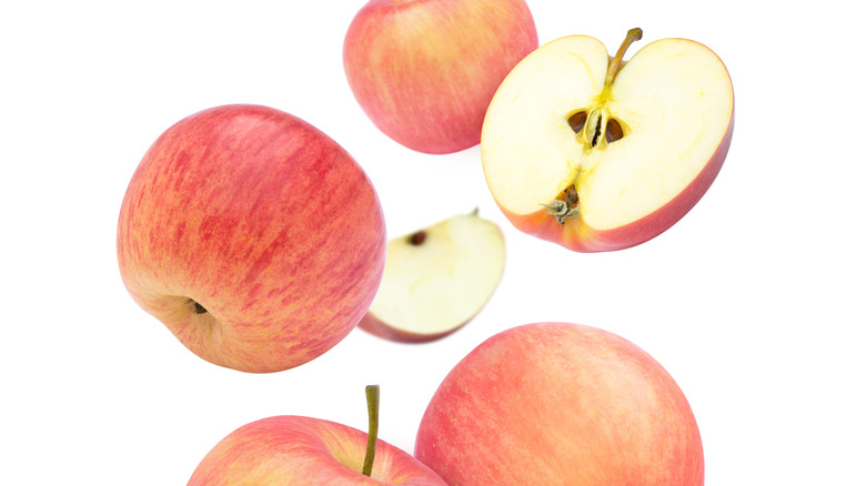 Fuji apples suspended against a white backdrop