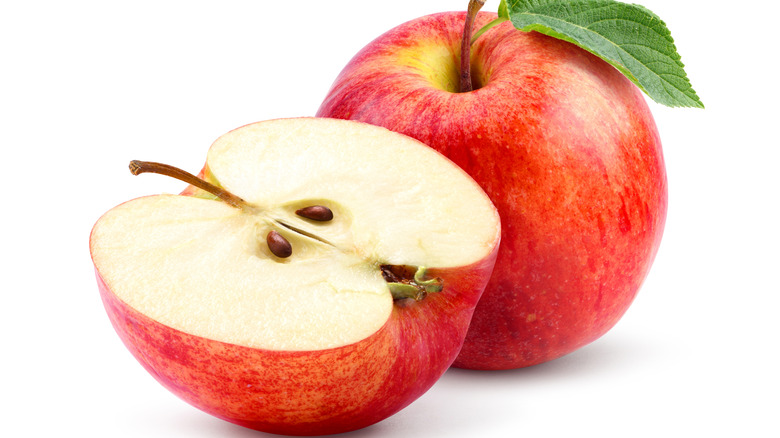 A whole and half Gala apple on white background