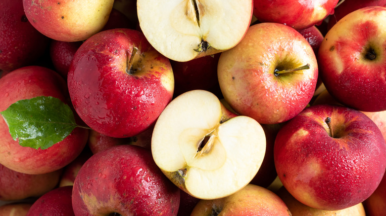 A pile of whole and half Jonathan apples with a green leaf