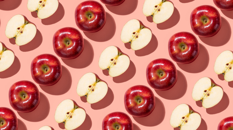 Red Delicious apples in rows set against pink backdrop