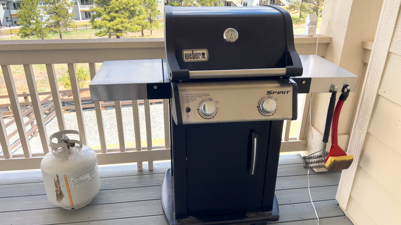 Front view of a Weber Spirit grill with attached propane tank placed on a balcony deck