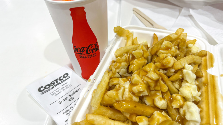 Meal at Costco food court includes Coca-Cola drink and poutine with fries, cheese curds, and gravy on white table