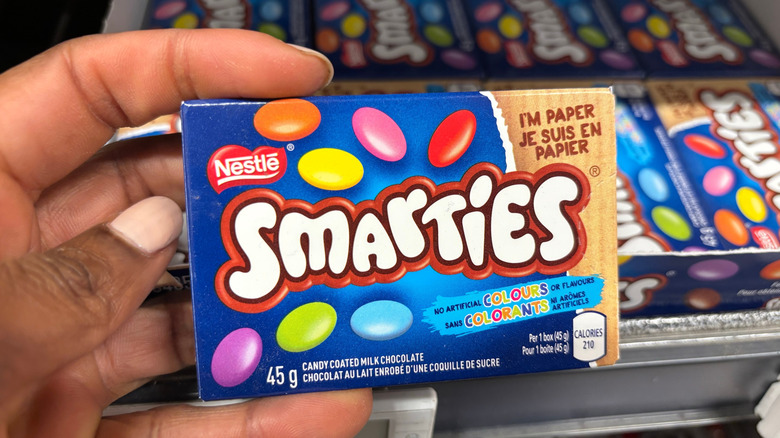 Person's hand holding a box of Smarties in store