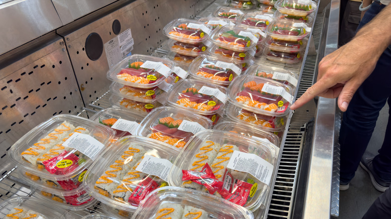 Hand pointing at trays of Costco sushi