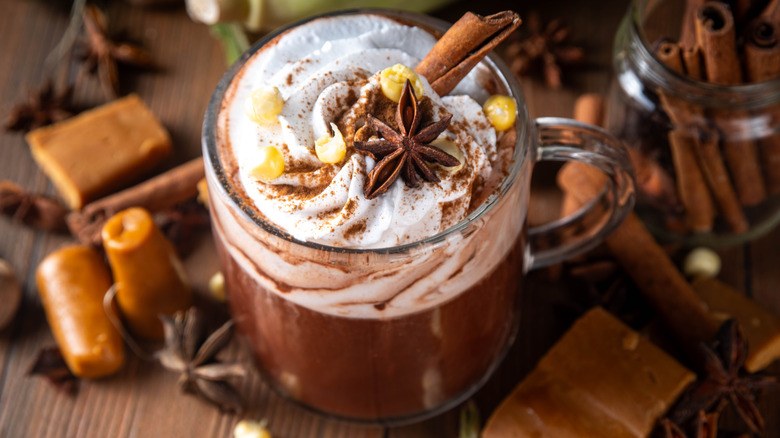 Mexican hot chocolate with star anise and cinnamon sticks on wooden table