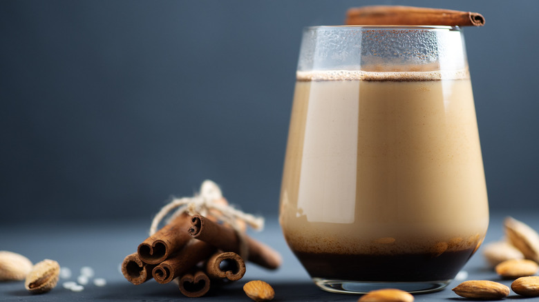 Horchata latte in clear glass with cinnamon sticks on gray background