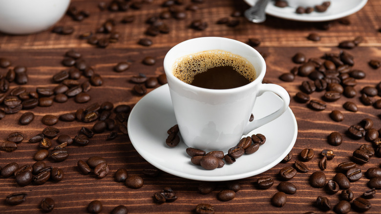 Cup of dark roasted coffee on a white saucer
