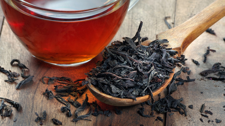 Dry leaves of black tea in wooden spoon