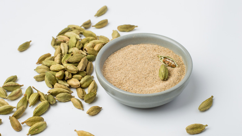 Ground cardamom and whole cardamom in a bowl