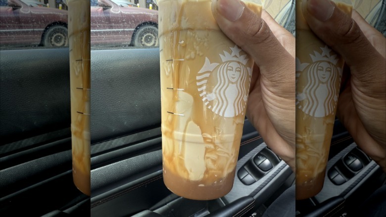 A hand holding up a venti Starbucks drink with 2 inches of caramel at the bottom of the cup