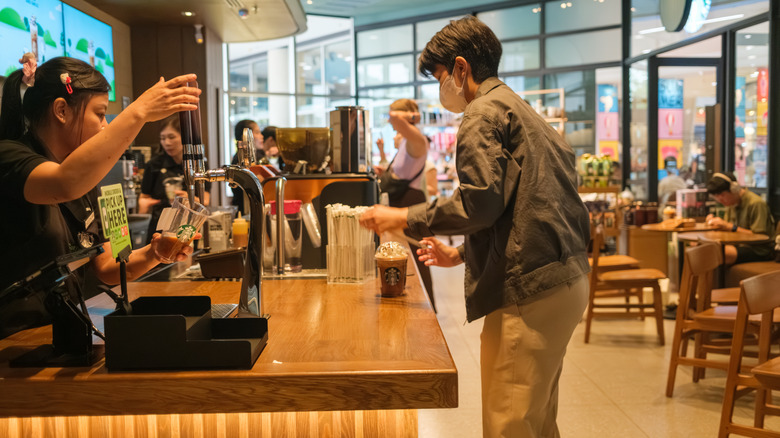 Customers collecting drinks at a busy Starbucks Café at Central Festival Chiang Mai, Thailand