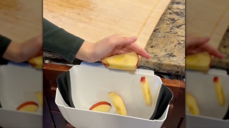 Person pushing apple scraps into trashcan
