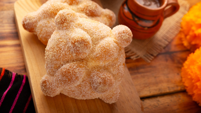 Pan de muerto Mexican breads on wooden cutting board