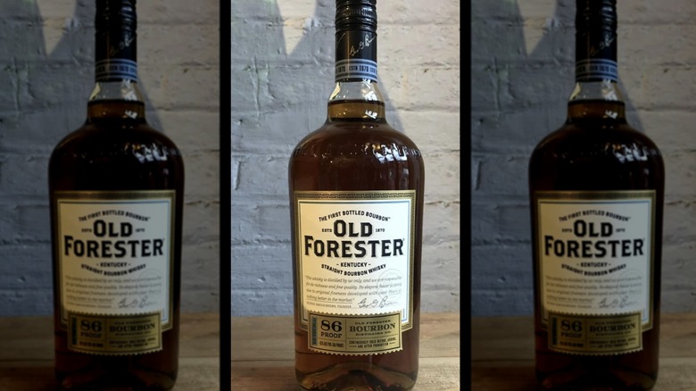 Old Forester 86 proof label on bottle in front of white brick wall