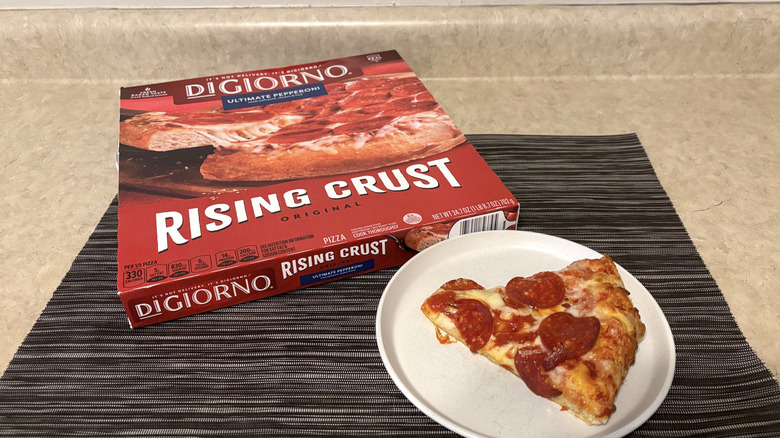 DiGiorno rising crust style pizza in box and slice on plate on black placemat