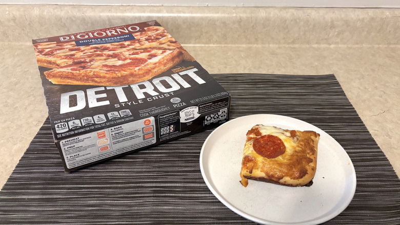 DiGiorno Detroit crust style pizza in box and slice on plate on black placemat