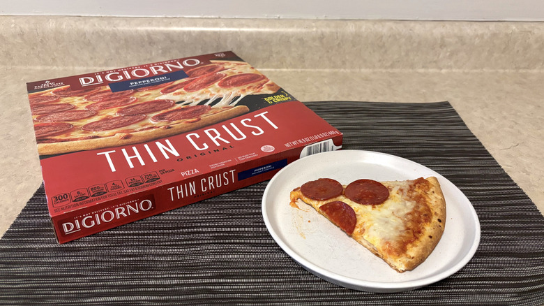DiGiorno thin crust style pizza in box and slice on plate on black placemat