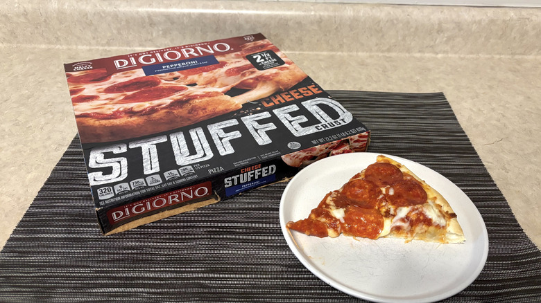 DiGiorno stuffed crust style pizza in box and slice on plate on black placemat