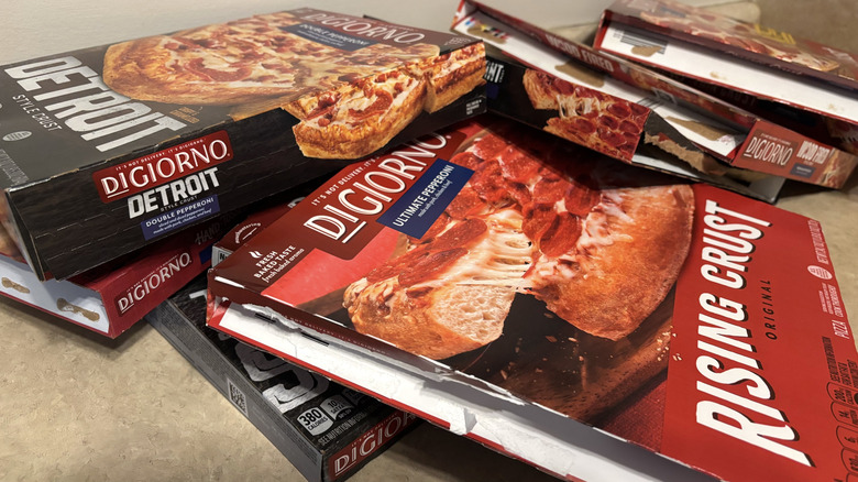 An assortment of DiGiorno style frozen pizzas in boxes on neutral background