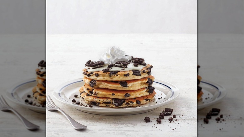 Oreo Oh My Goodness IHOP pancakes stacked on white plate topped with cream and crushed Oreos