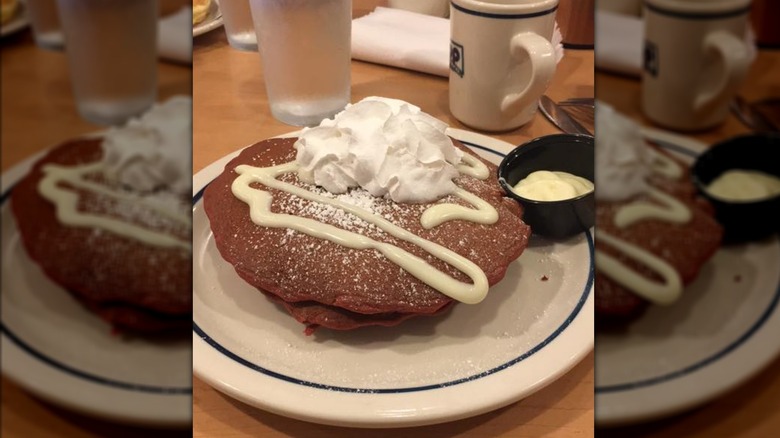 Red velvet pancakes from IHOP on white plate with whipped cream