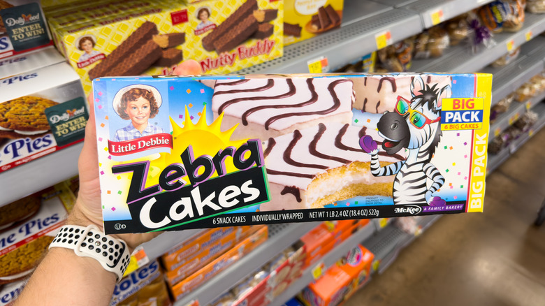Hand holding box of Little Debbie Zebra Cakes in grocery store