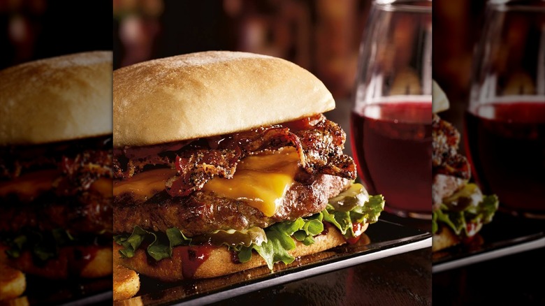 Burger with pepper-crusted bacon, melty cheese, shredded lettuce, and pickles
